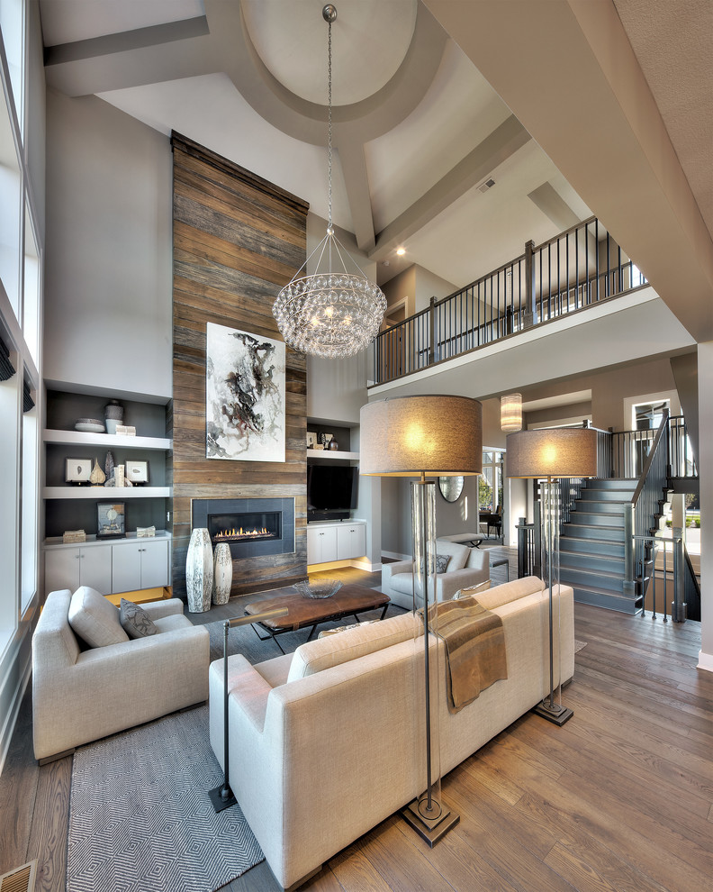 Traditional formal open plan living room in Kansas City with grey walls, medium hardwood flooring, a ribbon fireplace, a metal fireplace surround, a freestanding tv, brown floors and feature lighting.