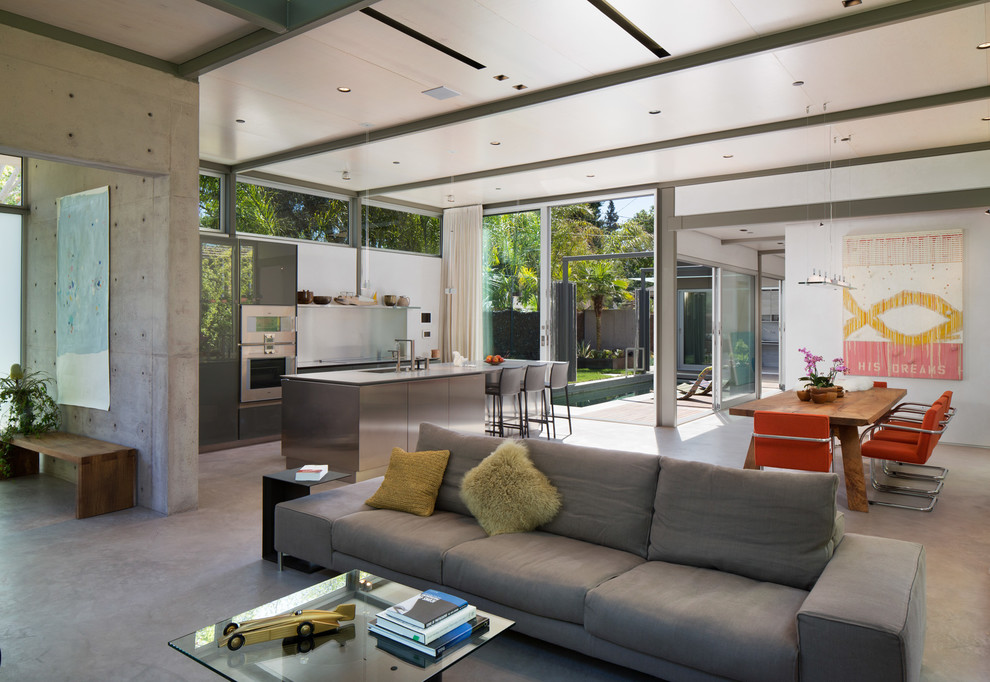 Immagine di un soggiorno minimalista di medie dimensioni e aperto con pareti bianche, pavimento in cemento e TV a parete