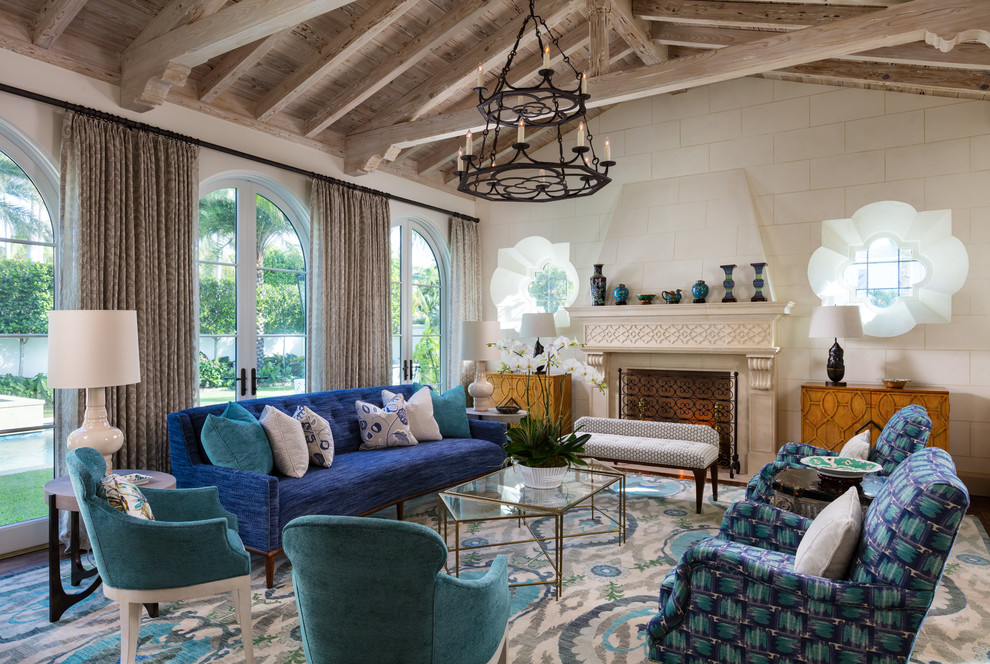 Идея дизайна: гостиная комната в средиземноморском стиле с бежевыми стенами, темным паркетным полом, стандартным камином, коричневым полом и синим диваном