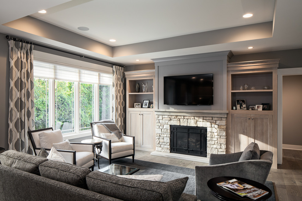Example of a mid-sized minimalist open concept medium tone wood floor and brown floor living room design in Grand Rapids with gray walls, a standard fireplace, a stone fireplace and a wall-mounted tv