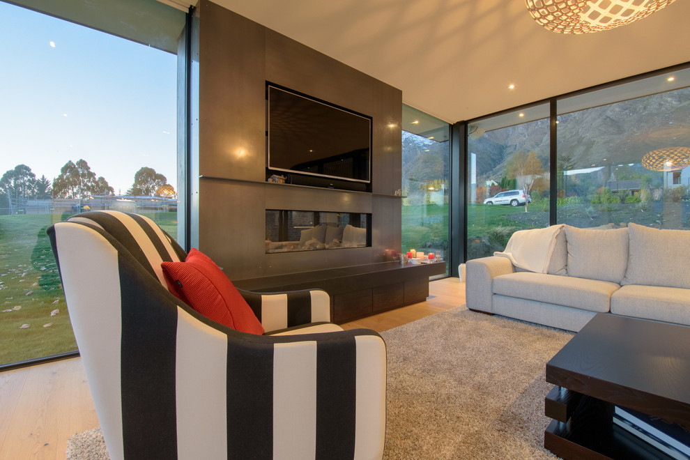 Immagine di un grande soggiorno minimalista aperto con sala formale, pareti bianche, parquet chiaro, parete attrezzata e pavimento marrone