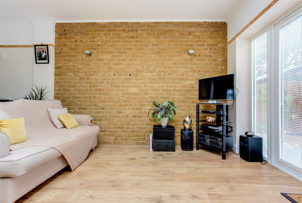 Стильный дизайн: гостиная комната среднего размера в современном стиле с бежевыми стенами, телевизором в углу и кирпичными стенами без камина - последний тренд