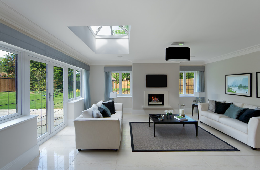 Immagine di un soggiorno design con pareti bianche, camino classico, TV a parete e pavimento bianco