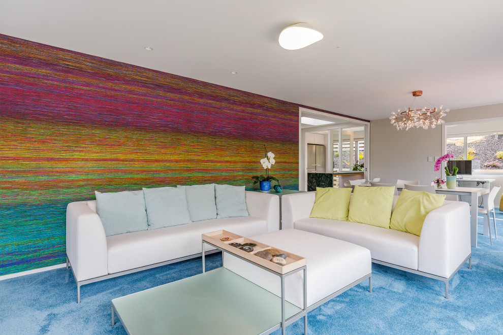 Стильный дизайн: большая открытая гостиная комната в современном стиле с белыми стенами, ковровым покрытием, отдельно стоящим телевизором и синим полом без камина - последний тренд