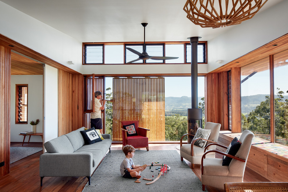 Esempio di un soggiorno moderno chiuso con pareti bianche, pavimento in legno massello medio, stufa a legna e tappeto
