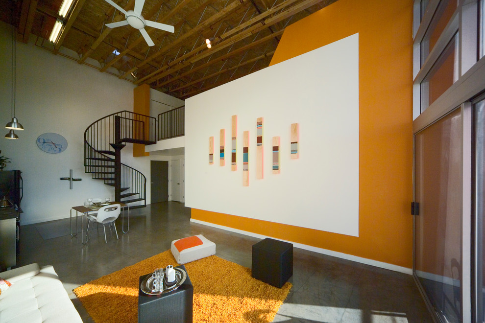 Inredning av ett modernt allrum med öppen planlösning, med orange väggar och betonggolv