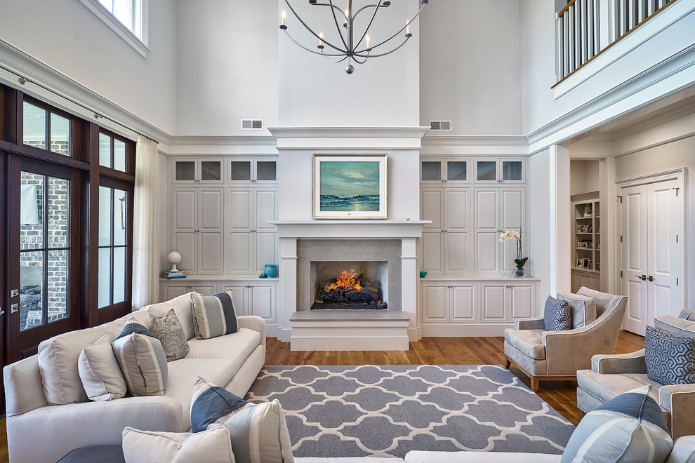 Стильный дизайн: открытая гостиная комната среднего размера в классическом стиле с серыми стенами, паркетным полом среднего тона, стандартным камином и фасадом камина из бетона - последний тренд