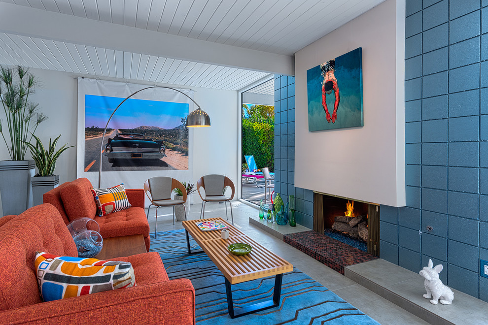На фото: парадная, открытая гостиная комната в стиле ретро с синими стенами, бетонным полом, стандартным камином и ковром на полу