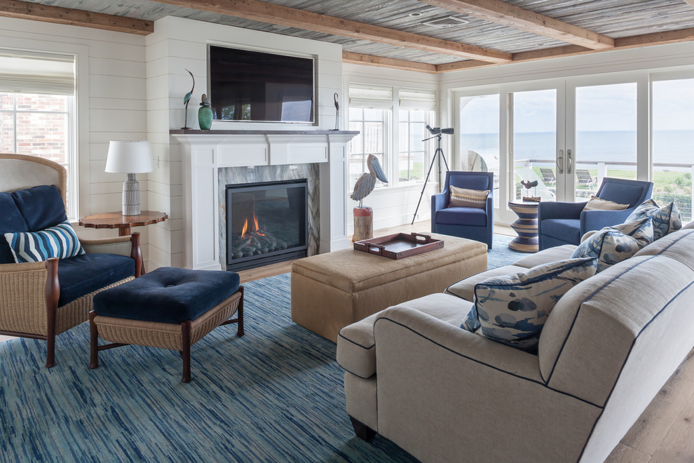Offenes Maritimes Wohnzimmer mit weißer Wandfarbe, braunem Holzboden, Kamin, Kaminumrandung aus Stein und braunem Boden in Bridgeport