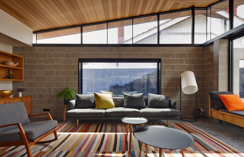 Cette image montre un salon design avec un mur gris et sol en béton ciré.
