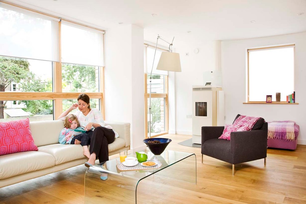 Exemple d'un salon tendance de taille moyenne et ouvert avec une salle de réception, un mur blanc, un sol en bois brun, un poêle à bois et un manteau de cheminée en métal.