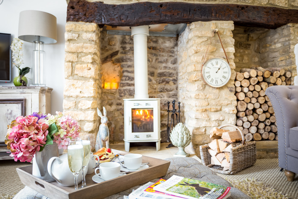Inspiration for a medium sized rustic formal enclosed living room in Gloucestershire with white walls, carpet, a wood burning stove, a stone fireplace surround and a freestanding tv.