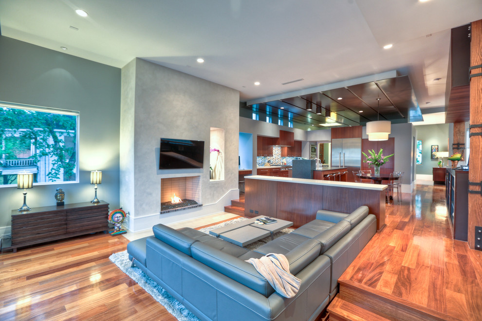 Photo of a large contemporary formal open plan living room in Houston with multi-coloured walls, medium hardwood flooring, a standard fireplace, a stone fireplace surround, a wall mounted tv and brown floors.