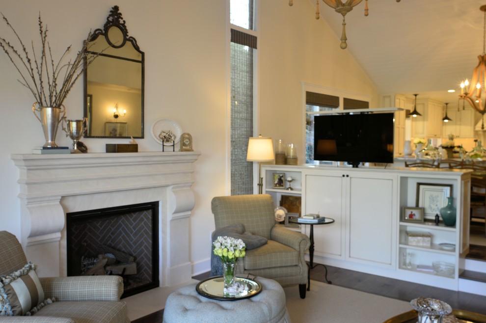 Cette image montre un grand salon traditionnel ouvert avec parquet foncé, une cheminée standard, un manteau de cheminée en pierre et un téléviseur dissimulé.