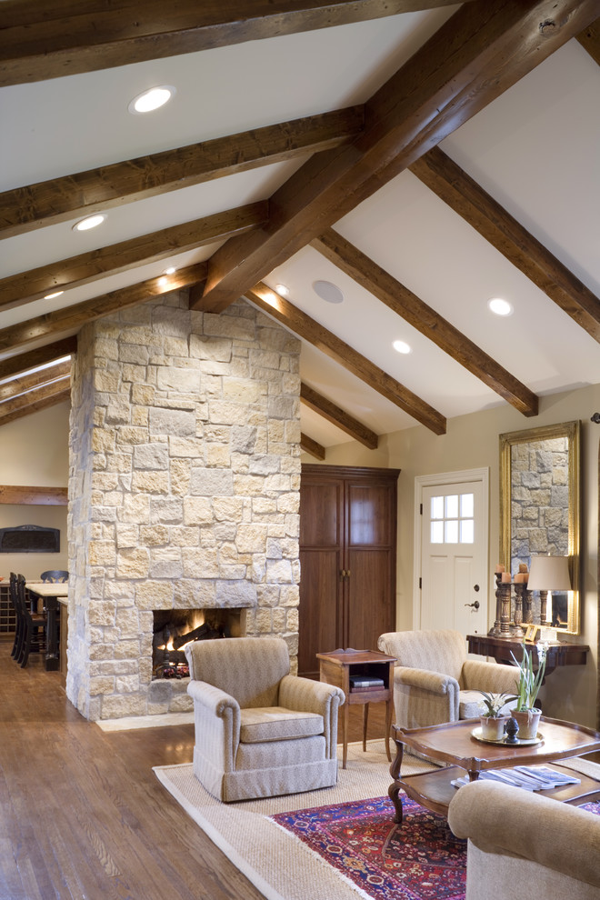 Large elegant open concept medium tone wood floor living room photo in Kansas City with beige walls, a standard fireplace, a stone fireplace and no tv