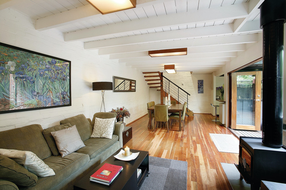 Immagine di un soggiorno tradizionale aperto con pareti bianche, pavimento in legno massello medio e camino classico