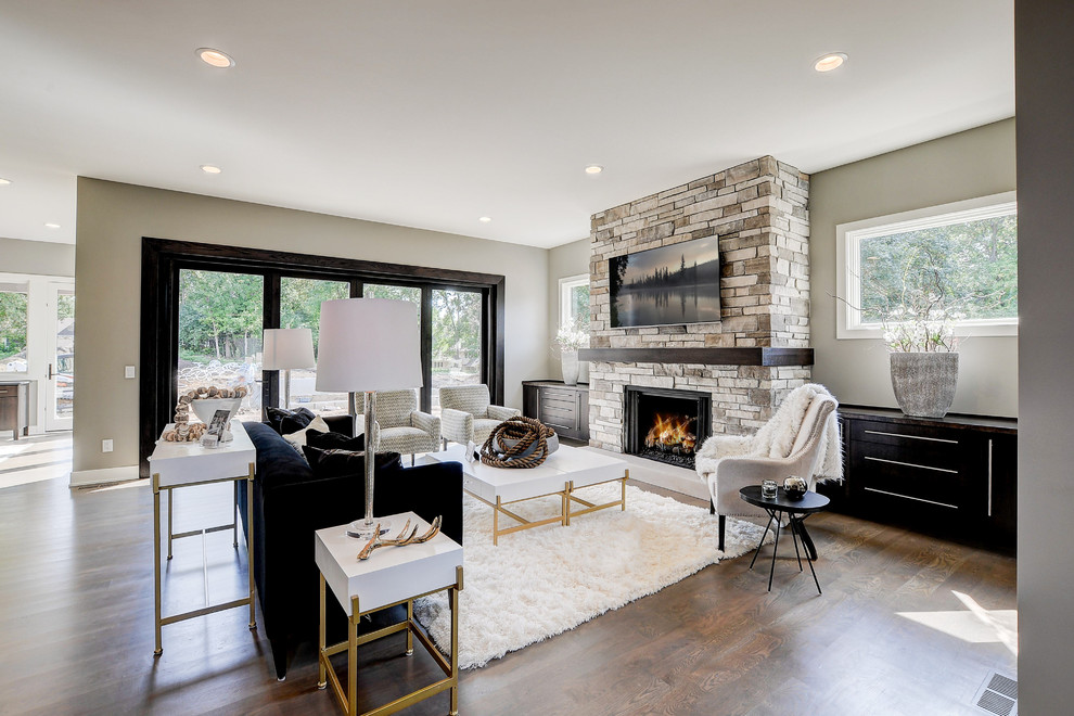 Inspiration pour un grand salon design ouvert avec un mur gris, parquet clair, une cheminée standard, un manteau de cheminée en pierre, un téléviseur fixé au mur et un sol marron.