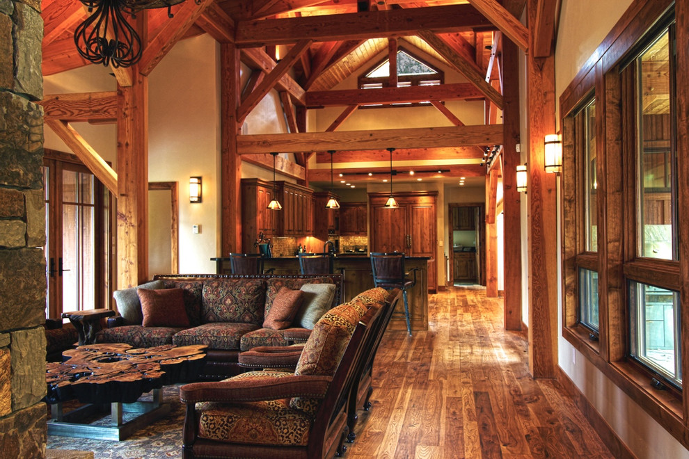 Immagine di un grande soggiorno stile rurale aperto con pareti beige, pavimento in legno massello medio, camino classico, cornice del camino in pietra e pavimento marrone