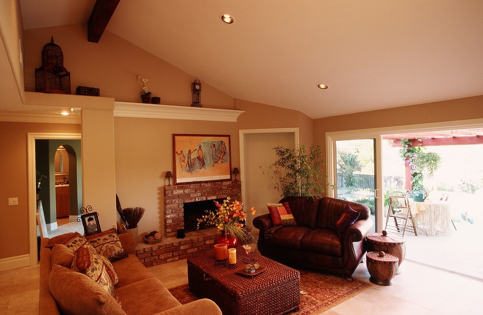 Exemple d'un grand salon craftsman avec un sol en calcaire, une cheminée standard, un manteau de cheminée en brique et un mur marron.