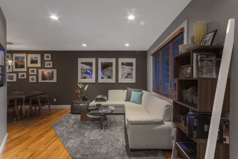This is an example of a small modern formal open plan living room in New York with grey walls, light hardwood flooring, no fireplace, a wall mounted tv and brown floors.