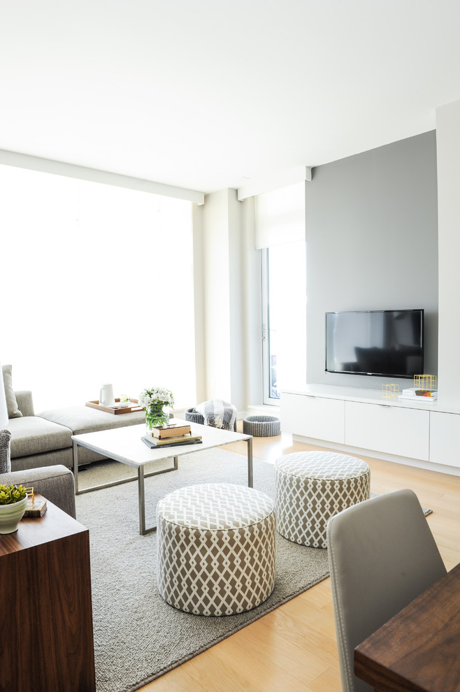 Offenes Skandinavisches Wohnzimmer mit grauer Wandfarbe, TV-Wand und hellem Holzboden in Vancouver