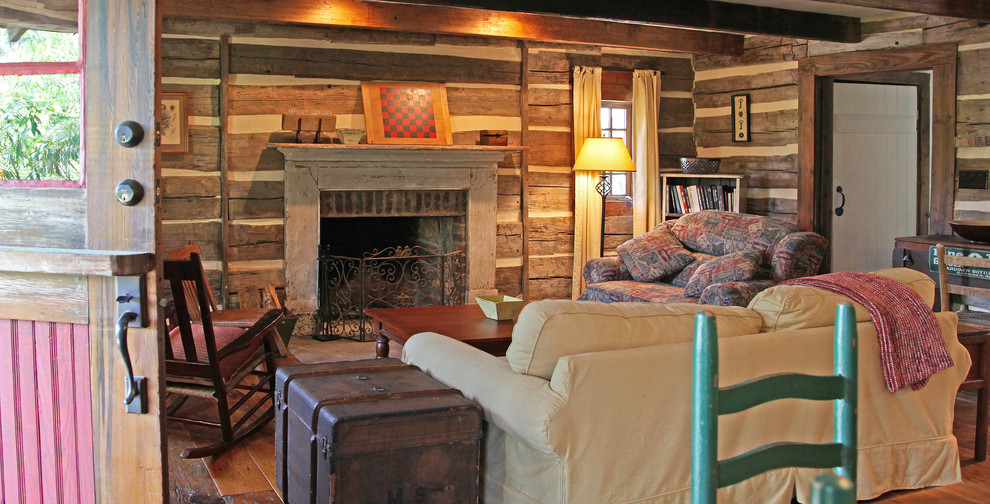 他の地域にある高級な中くらいなラスティックスタイルのおしゃれな独立型リビング (茶色い壁、濃色無垢フローリング、標準型暖炉、木材の暖炉まわり) の写真