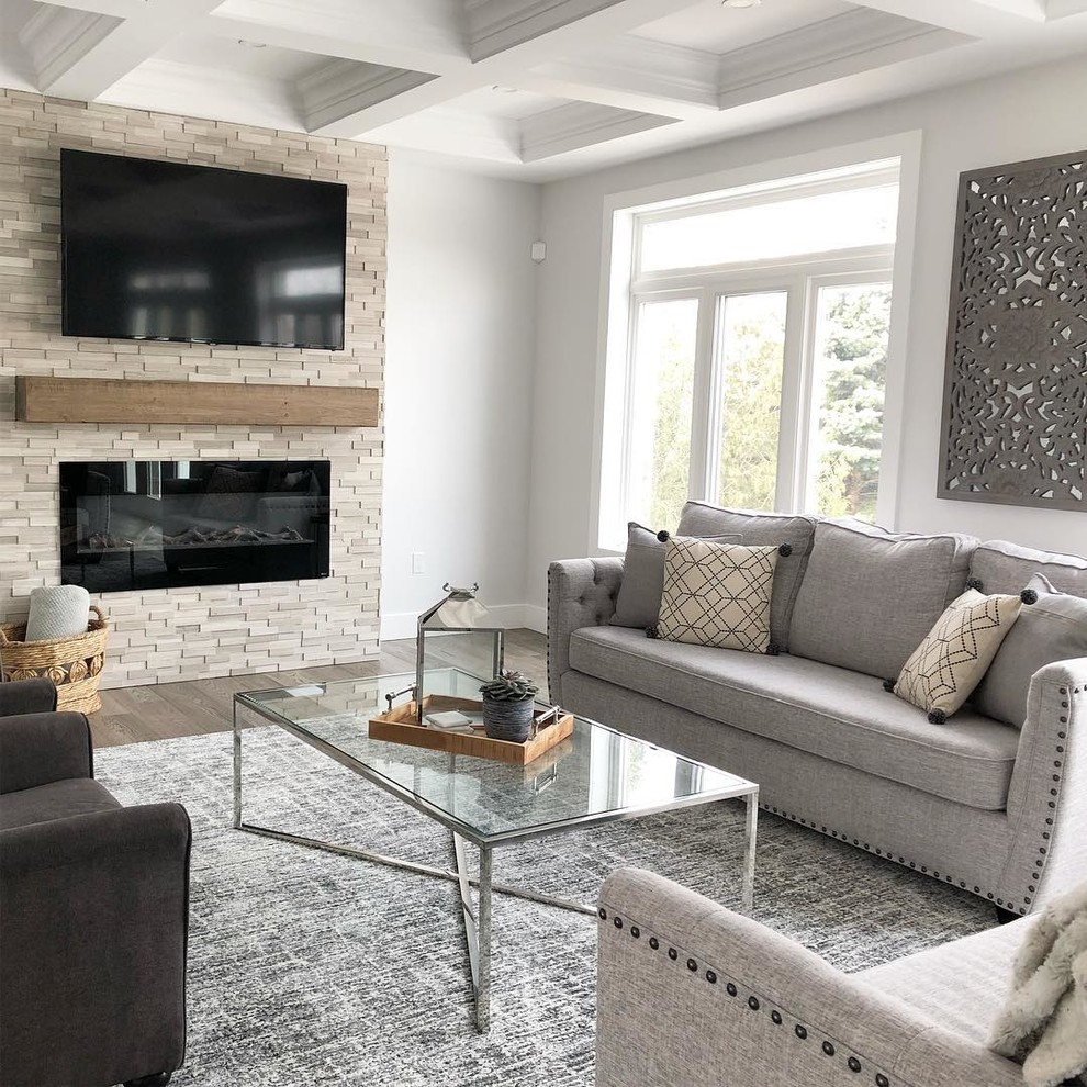 Klassisk inredning av ett stort separat vardagsrum, med vita väggar, mellanmörkt trägolv, en standard öppen spis, en spiselkrans i sten, en väggmonterad TV och brunt golv