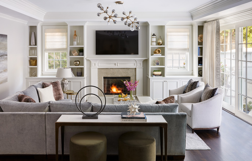 Klassisches Wohnzimmer mit weißer Wandfarbe, braunem Holzboden, Kamin, Kaminumrandung aus Stein, TV-Wand und braunem Boden in Los Angeles