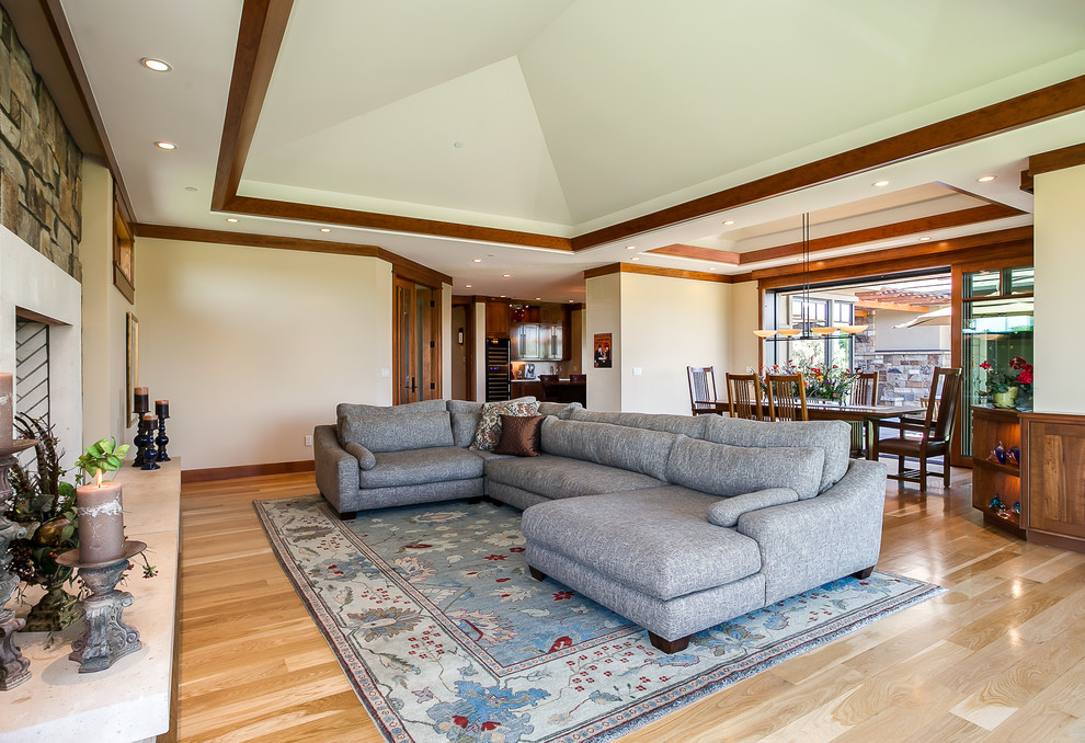 Example of a mid-sized arts and crafts open concept light wood floor living room design in Denver with beige walls, a standard fireplace, a stone fireplace and no tv