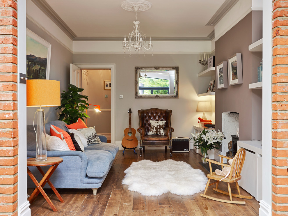 Kleines, Abgetrenntes Klassisches Wohnzimmer mit beiger Wandfarbe, braunem Holzboden, Kaminofen, braunem Boden und Kaminumrandung aus Backstein in Sonstige