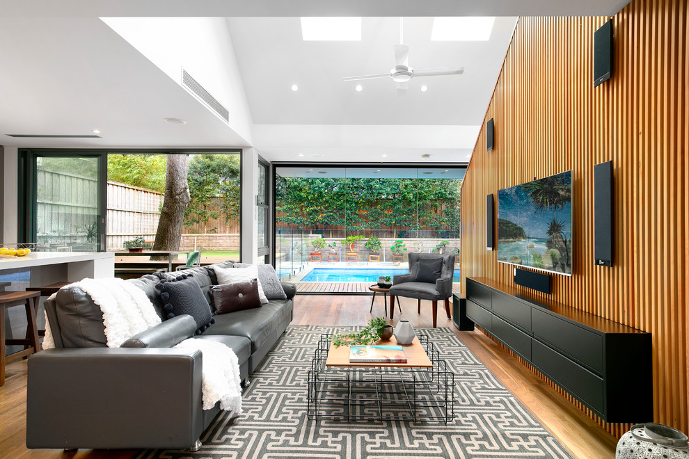 Exempel på ett mellanstort modernt allrum med öppen planlösning, med vita väggar, mellanmörkt trägolv, en väggmonterad TV och brunt golv