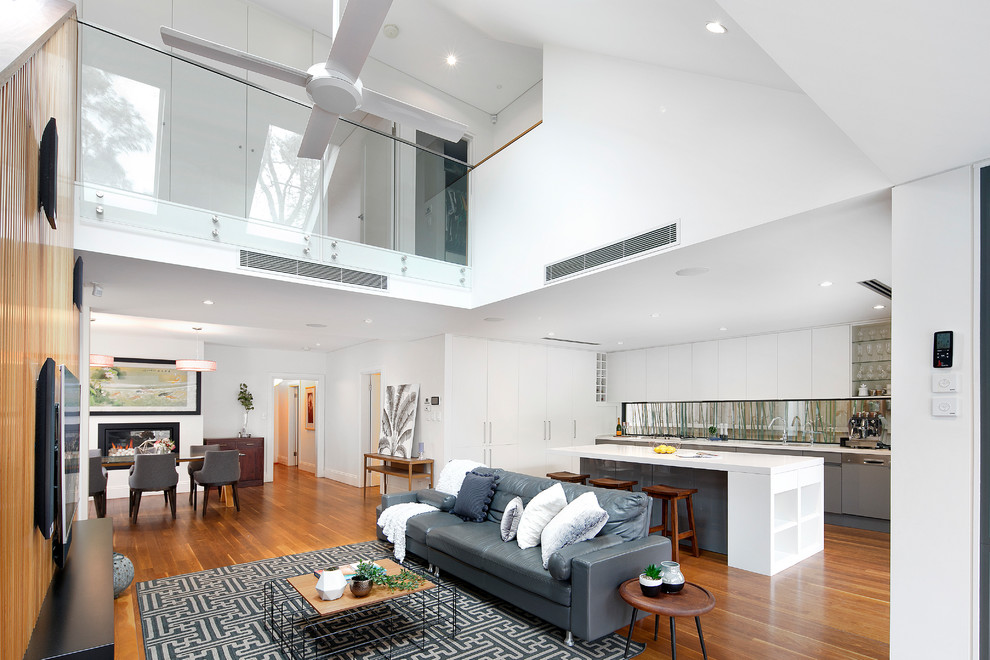 Modern open plan living room in Sydney with white walls, medium hardwood flooring, a ribbon fireplace, a metal fireplace surround, a wall mounted tv and brown floors.