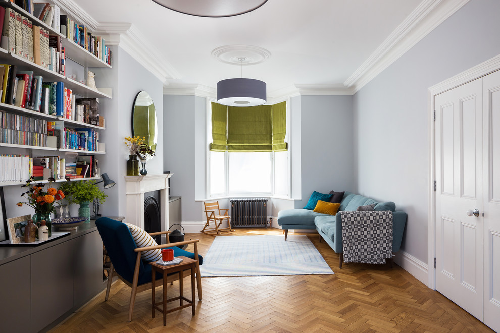 Design ideas for a contemporary grey and teal open plan living room in London with grey walls, a reading nook, medium hardwood flooring and a standard fireplace.