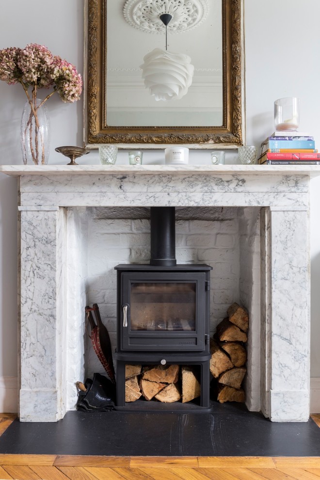 This is an example of a medium sized traditional open plan living room in London with a reading nook, multi-coloured walls, dark hardwood flooring, a wood burning stove, a stone fireplace surround and a built-in media unit.