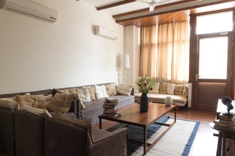 Esempio di un soggiorno minimal di medie dimensioni e aperto con pareti beige, pavimento in legno massello medio e TV a parete