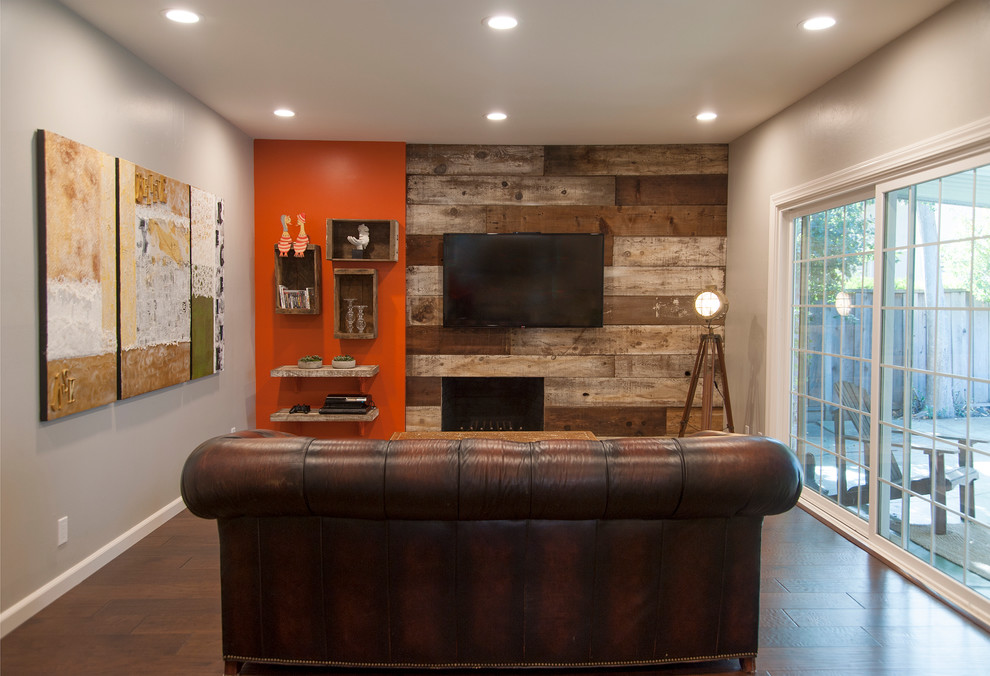 На фото: изолированная гостиная комната среднего размера в стиле рустика с оранжевыми стенами, темным паркетным полом, стандартным камином и фасадом камина из дерева