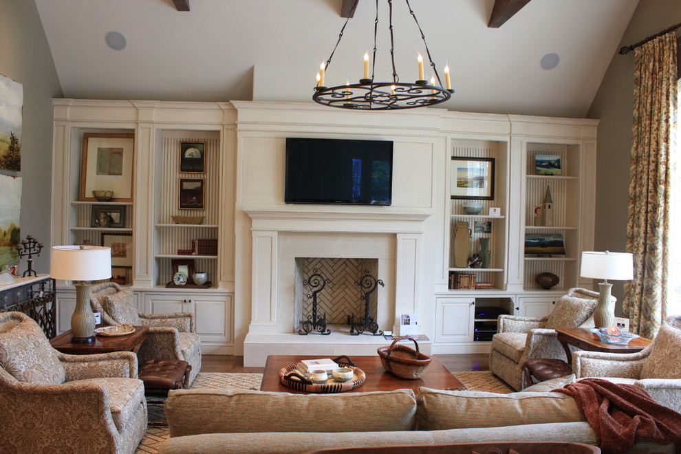 Cette image montre un grand salon traditionnel avec une cheminée standard, un téléviseur fixé au mur et éclairage.