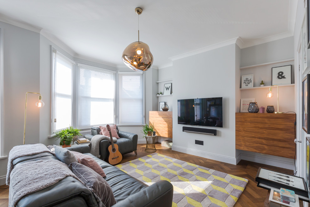 Mittelgroßes, Abgetrenntes Modernes Wohnzimmer mit grauer Wandfarbe, TV-Wand und braunem Holzboden in London
