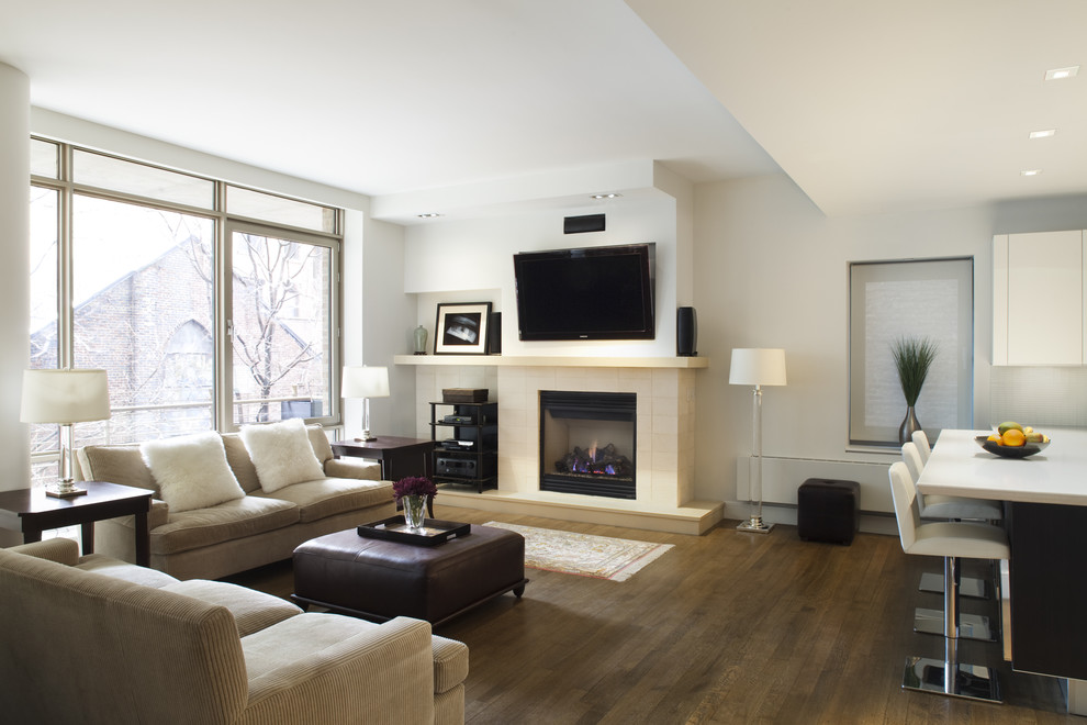 На фото: открытая гостиная комната в современном стиле с белыми стенами, темным паркетным полом, стандартным камином и телевизором на стене