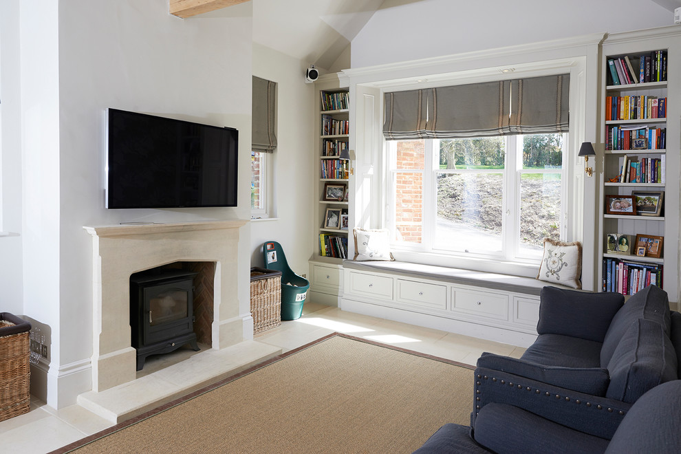 Mittelgroßes, Offenes Country Wohnzimmer mit weißer Wandfarbe, Kalkstein, Kaminofen, Kaminumrandung aus Stein, TV-Wand und beigem Boden in Hampshire
