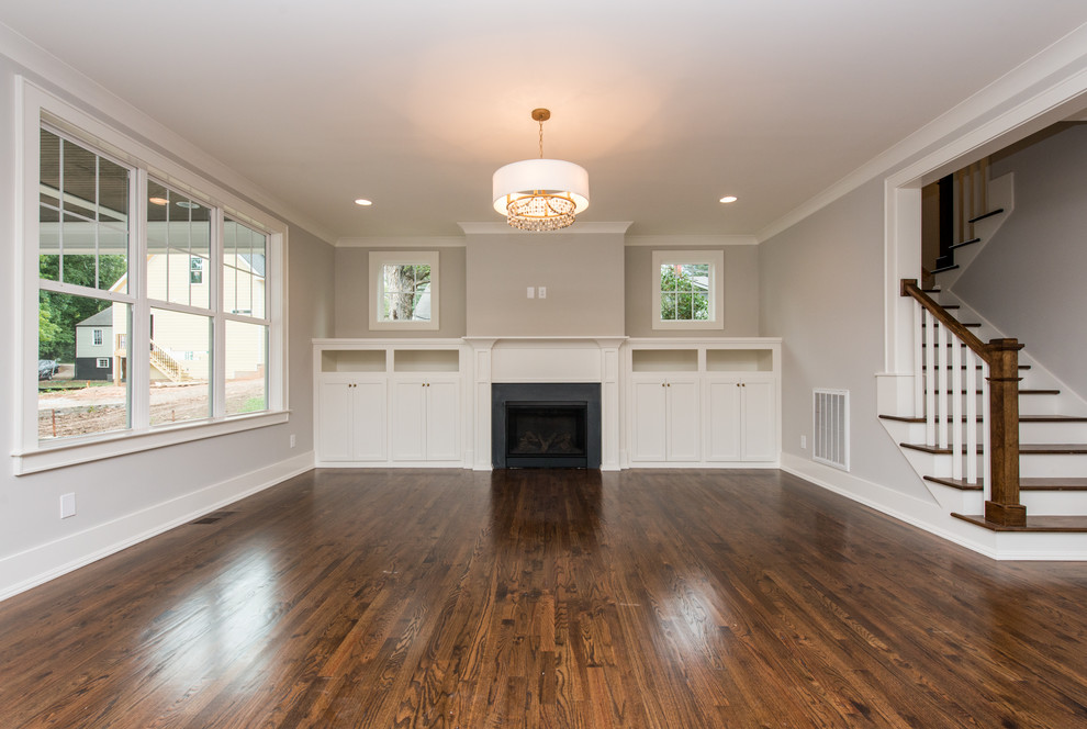 Example of a large classic open concept medium tone wood floor living room design in Raleigh with gray walls, a standard fireplace, a stone fireplace and a wall-mounted tv