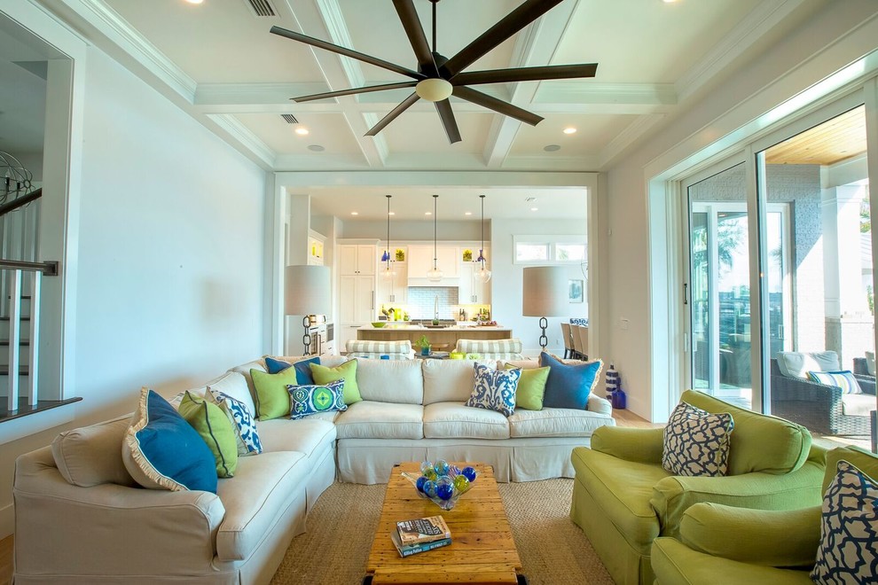 Example of a large beach style open concept light wood floor living room design in Jacksonville with white walls, a standard fireplace, a brick fireplace and a wall-mounted tv