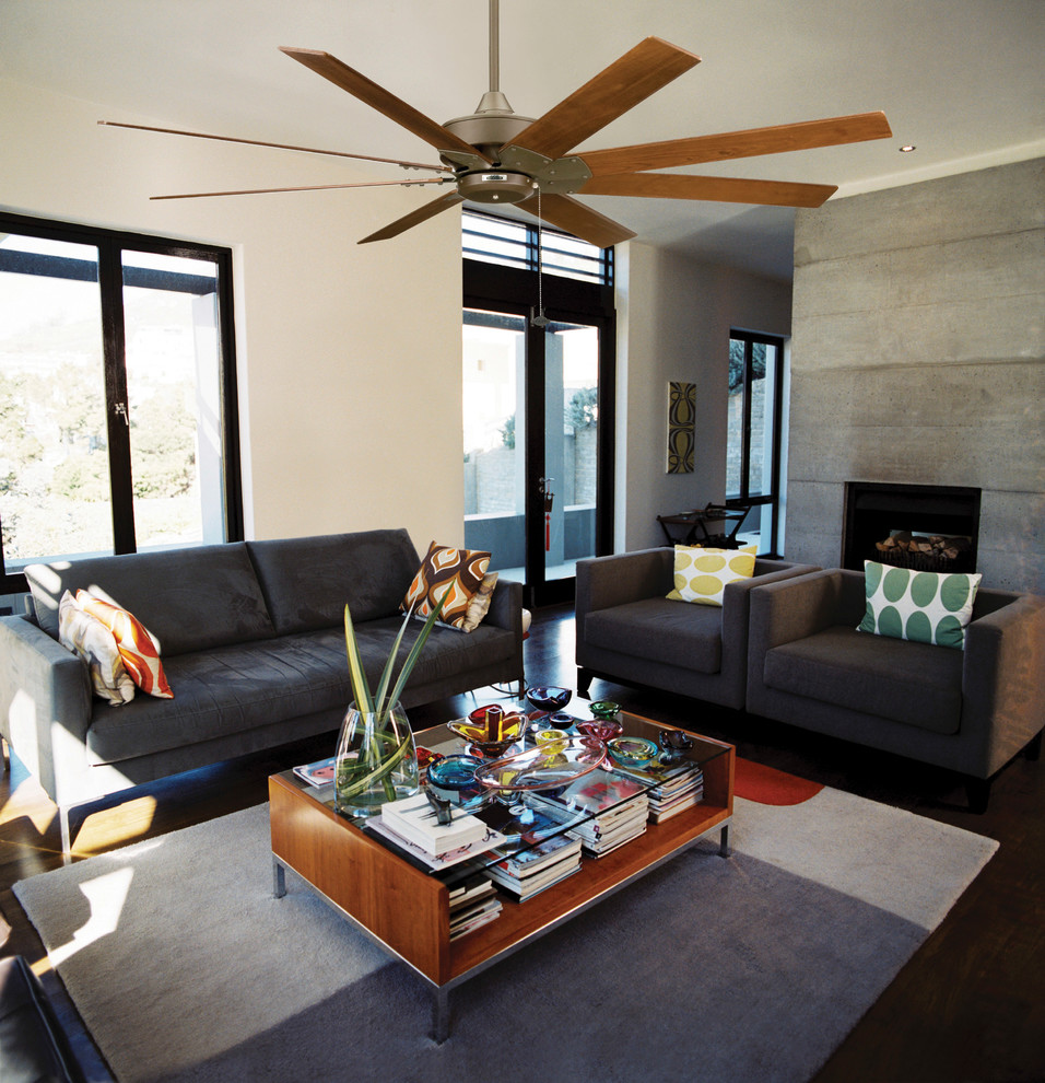 Photo of a large modern formal enclosed living room in San Diego with beige walls, dark hardwood flooring, a standard fireplace, a concrete fireplace surround and no tv.