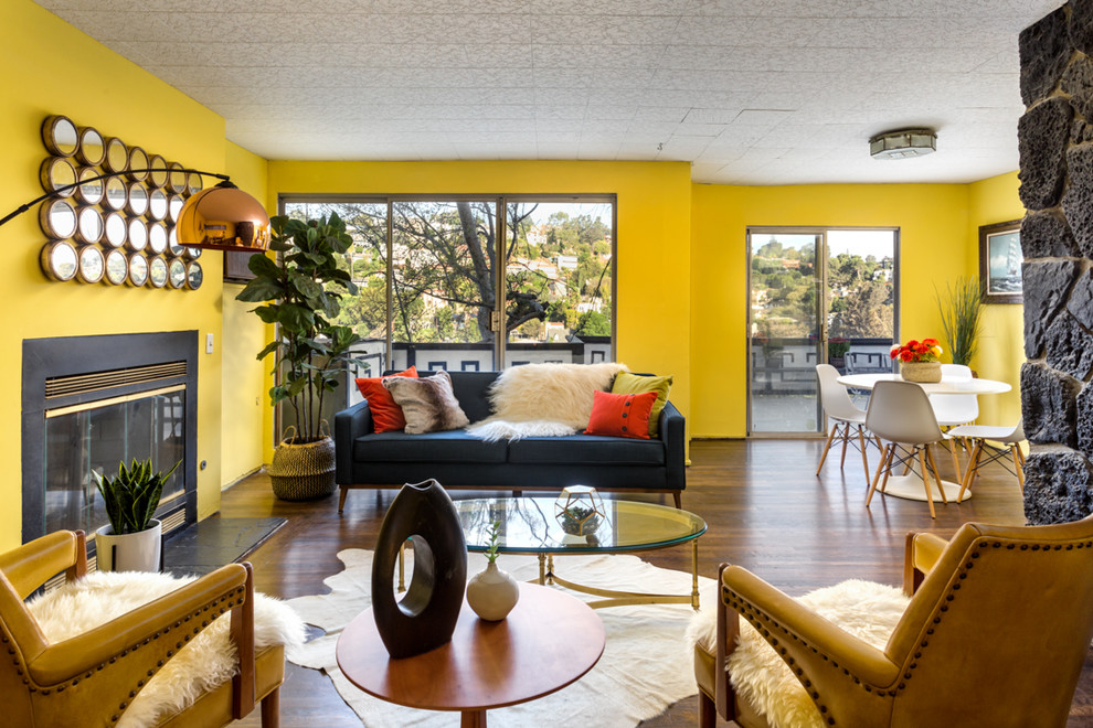Retro inredning av ett vardagsrum, med gula väggar, mörkt trägolv och en standard öppen spis