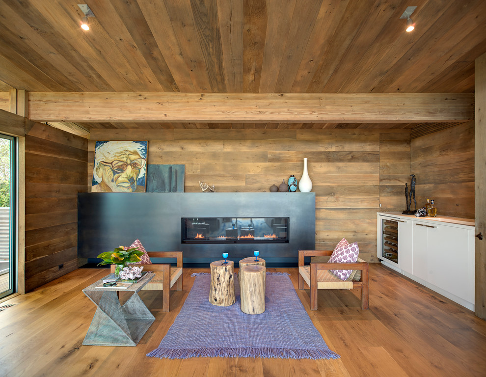 Bild på ett funkis vardagsrum, med bruna väggar, mellanmörkt trägolv, en bred öppen spis och en hemmabar
