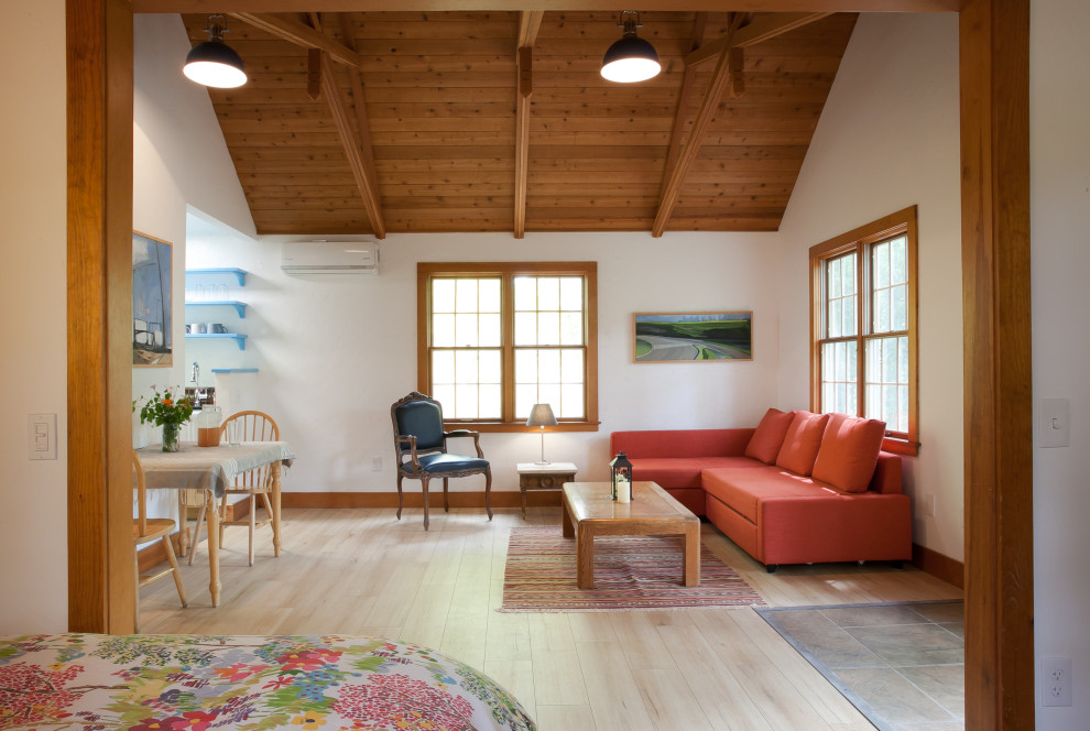 Immagine di un soggiorno country aperto con pavimento in laminato, pareti bianche, camino ad angolo, pavimento beige, soffitto a volta e soffitto in legno