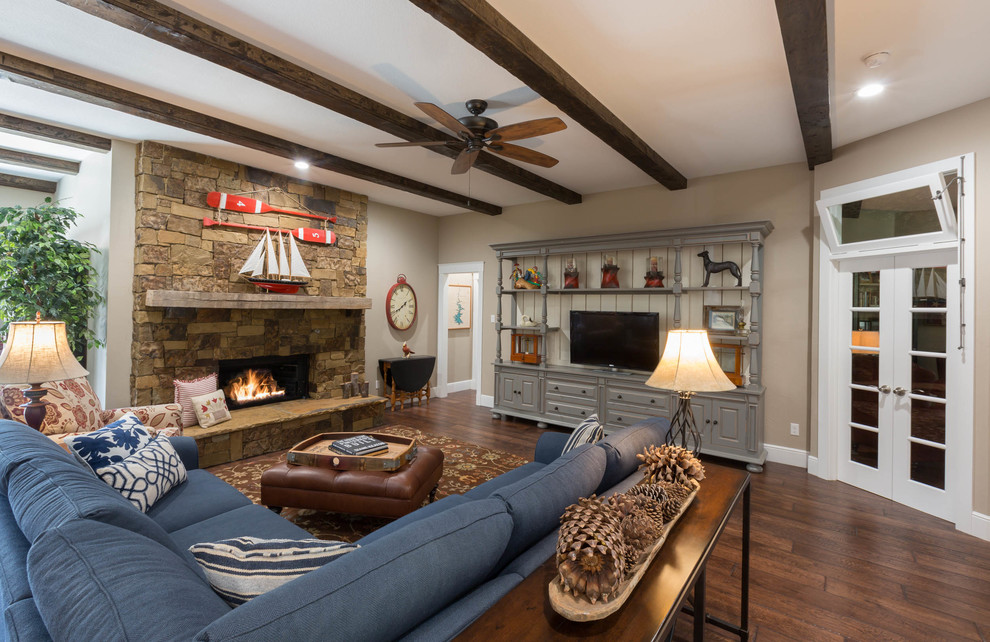 Offenes Landhausstil Wohnzimmer mit beiger Wandfarbe, braunem Holzboden, Kamin, Kaminumrandung aus Stein, freistehendem TV und braunem Boden in Dallas
