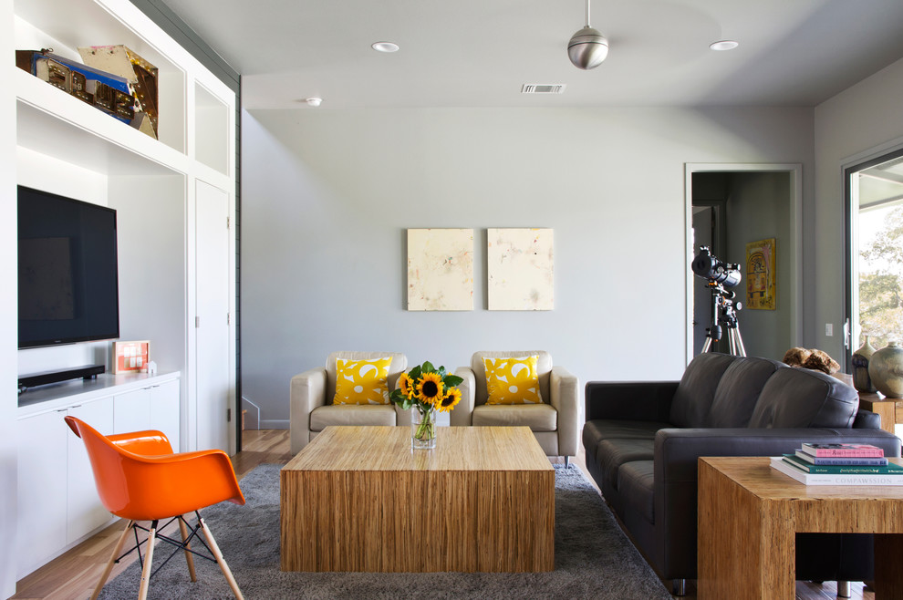 Repräsentatives Country Wohnzimmer mit grauer Wandfarbe, braunem Holzboden und TV-Wand in Austin