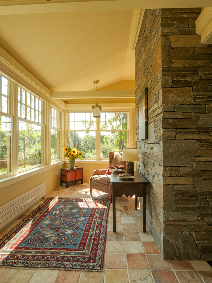 Ejemplo de salón abierto de estilo de casa de campo con paredes amarillas, todas las chimeneas, marco de chimenea de piedra y televisor retractable