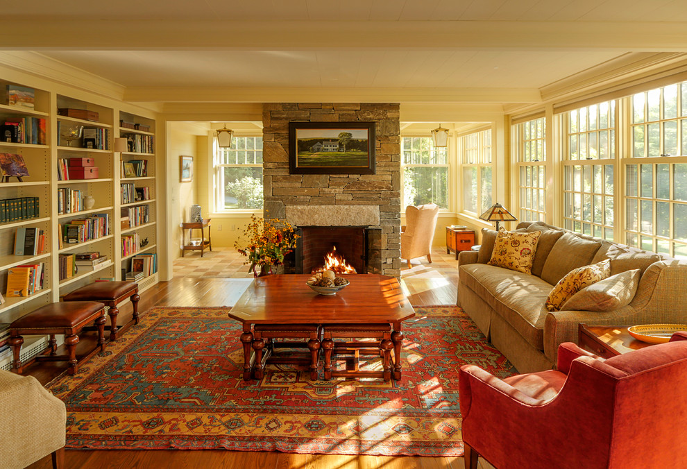 Exemple d'un salon nature ouvert avec une bibliothèque ou un coin lecture, un mur jaune, une cheminée standard, un manteau de cheminée en pierre et aucun téléviseur.